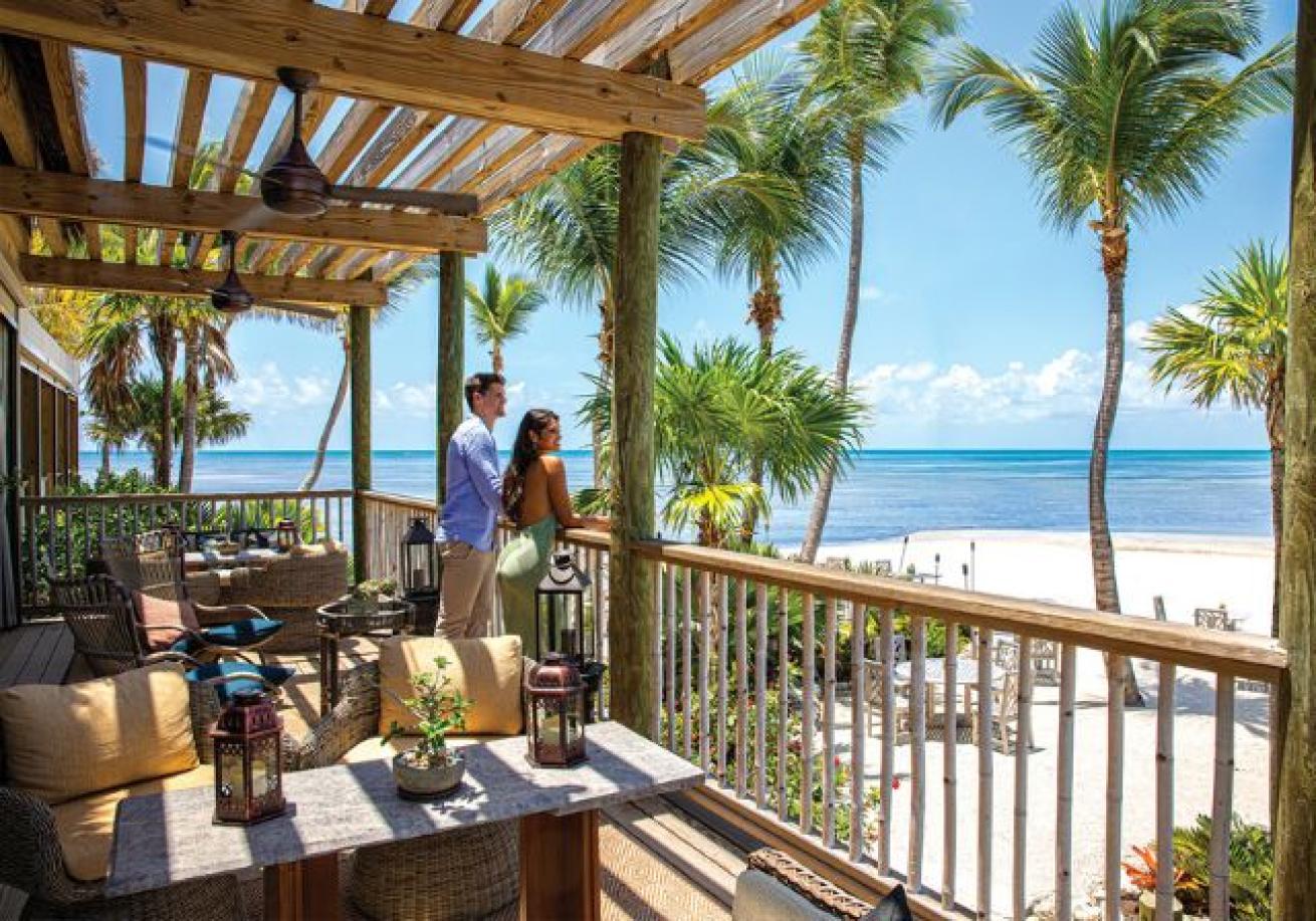 A couple standing on a deck overlooking a beach